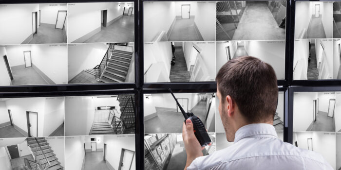 Young,Male,Security,Guard,Talking,On,Walkie-talkie,While,Monitoring,Multiple